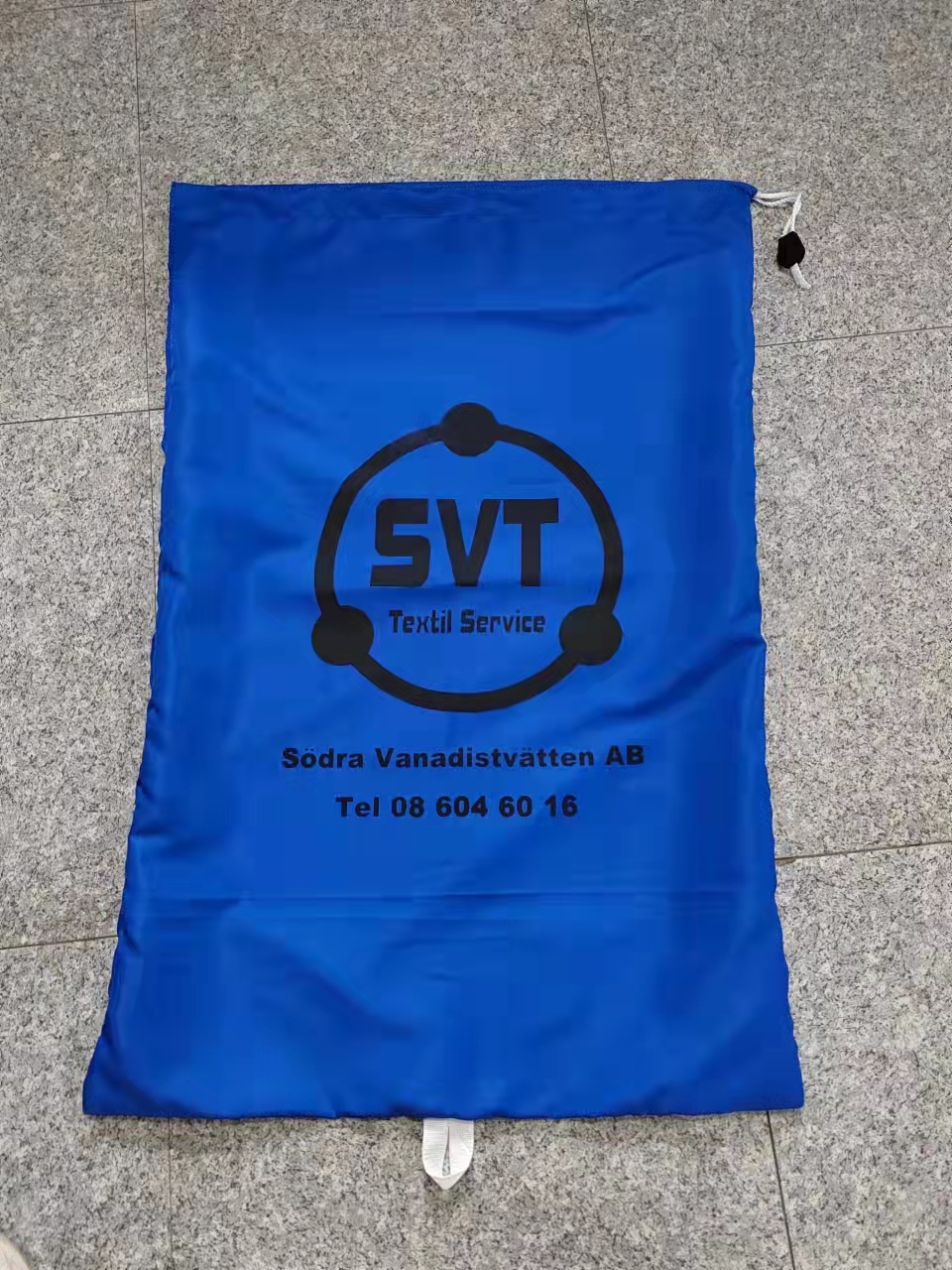 Blue industrial laundry bag with black SVT Textil Service logo screen print